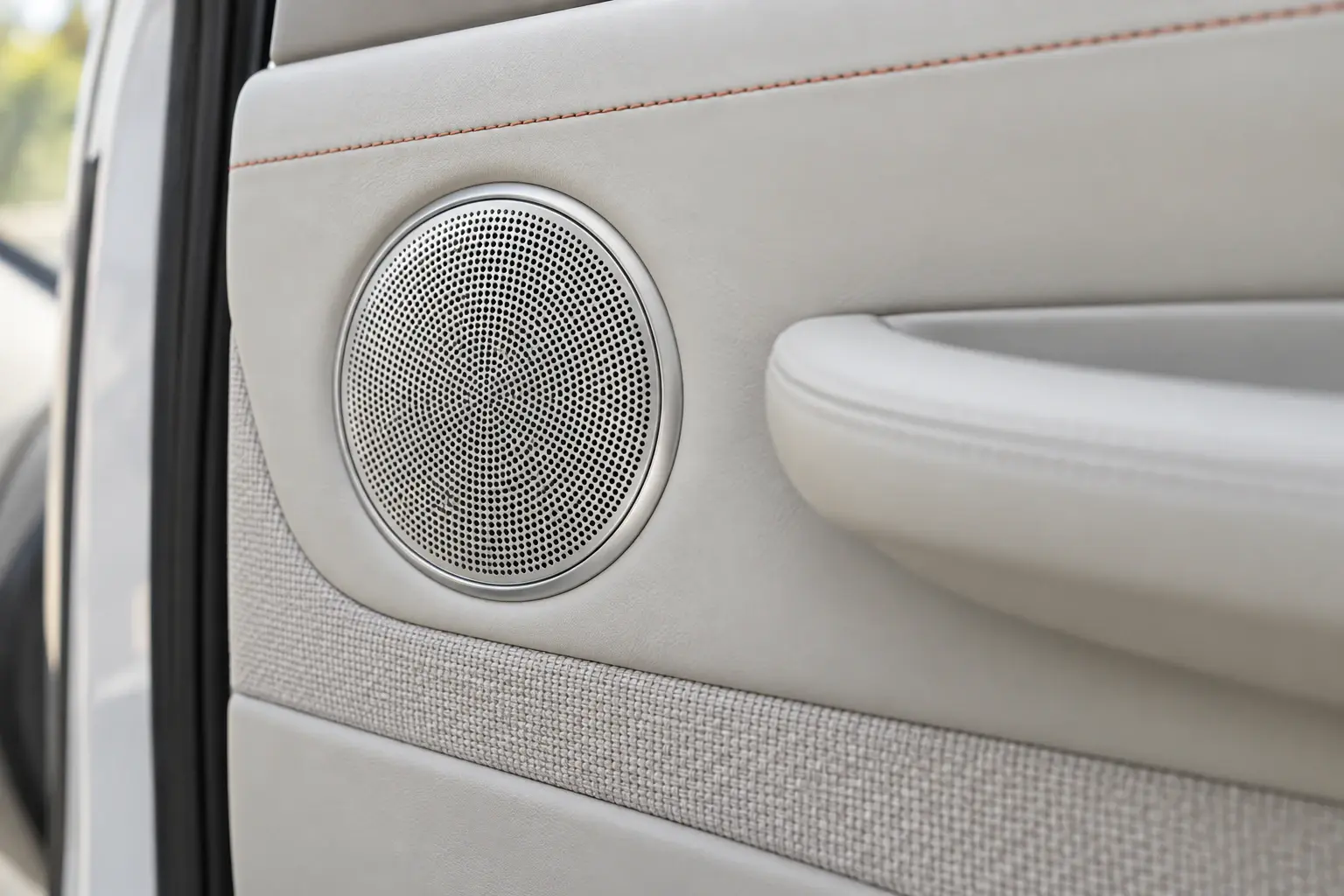 Illustration: a round speaker grille in a car door.